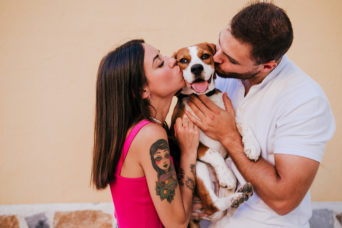 Happy Couple Kissing Their Beagle Dog 